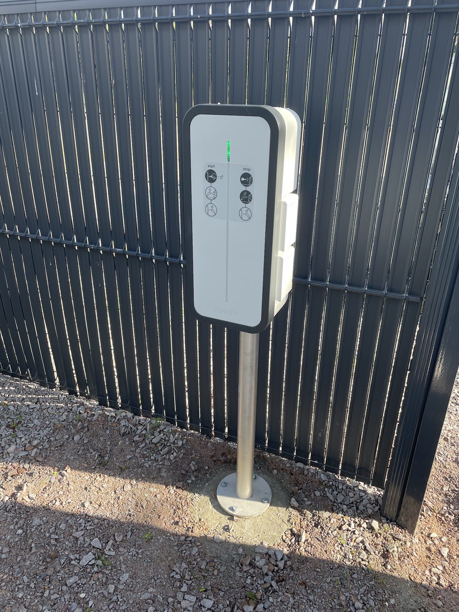 Borne de recharge posée sur pied devant une clôture